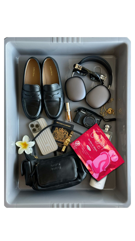 A flat lay photo of travel essentials in an airport security tray