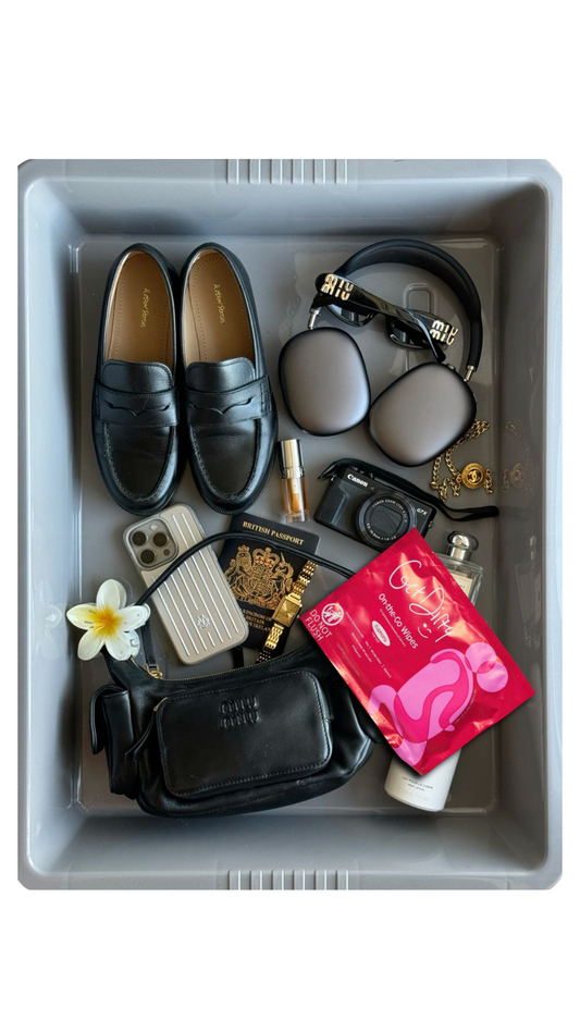 A flat lay photo of travel essentials in an airport security tray 